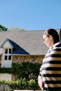 a woman walking in front of a house at Maison Hyacinthe in Saint-Pierre-Langers