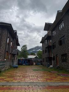 an empty courtyard between two buildings with mountains in the background at Himalayan Stay in Sonāmarg
