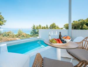 a table with a bowl of fruit next to a pool at Gloria Luxury Suites in Kallithea Halkidikis