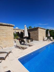 ein Pool mit Liegestühlen und Sonnenschirmen neben einem Gebäude in der Unterkunft Spanos House in Goudhi