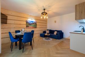 a living room with a table and a blue couch at Apartamenty Wiktorówka in Poronin