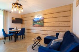 a living room with a blue couch and a table at Apartamenty Wiktorówka in Poronin