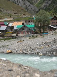 a group of houses and a river in a village at Himalayan Stay in Sonāmarg
