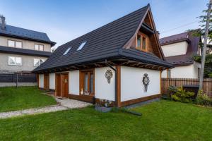 a house with a black roof and a yard at Apartamenty Wiktorówka in Poronin