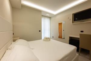 a white bedroom with two beds and a television at Hotel Twins in Vasto