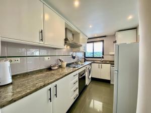 a kitchen with white cabinets and a white refrigerator at Luxurious apartment seafront Moraira by Moraira Holiday Homes in Moraira