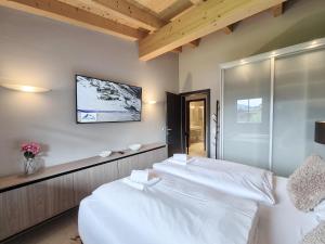 a bedroom with two white beds and a tv on the wall at Peak View Penthouse Kaprun in Kaprun