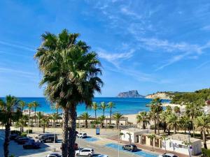 a palm tree in a parking lot next to the beach at Luxurious apartment seafront Moraira by Moraira Holiday Homes in Moraira