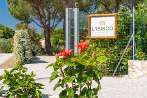 a sign in a garden with flowers next to a bush at Agricamping L'Ibisco in Riotorto
