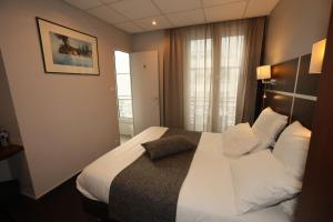 a hotel room with a bed with white sheets and pillows at Hôtel Des Trois Gares in Paris