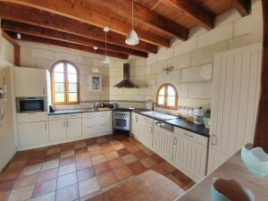 a large kitchen with white cabinets and wooden ceilings at Le Clos de La Réserve in Cinq-Mars-la-Pile