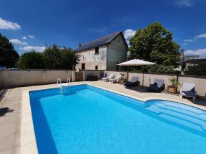 a swimming pool with two chairs and an umbrella at Le Clos de La Réserve in Cinq-Mars-la-Pile