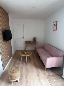 a living room with a pink couch and a table at L'escale Cognaçaise in Cognac