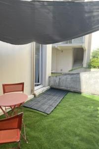 a patio with a table and chairs and grass at La Parenthèse Calme in Tours