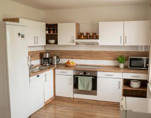 a white kitchen with white cabinets and a sink at Chata Pod Hájkem in Vrchlabí