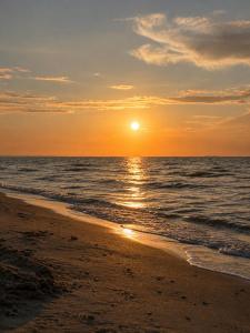 a sunset on a beach with the ocean at Domek na Morskiej in Jantar