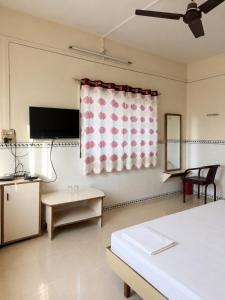 a room with a bed and a window with a curtain at Hotel Shree Jay Amba Deluxe in Jaisingpur