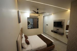 a bedroom with a bed and a flat screen tv at Ace Inn Hotel in Nagpur +19 photos