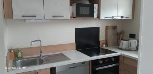 a small kitchen with a sink and a microwave at Suite-Appart Beau Soleil - 24H Le Mans Métropole in Allonnes