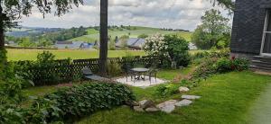 a garden with a table and a fence and flowers at Ferienhaus VILLA ZAUBERBLICK am Rennsteig Frankenwald FREISTEHEND naturnah HUNDEFREUNDLICH eingezäunt in Ludwigsstadt