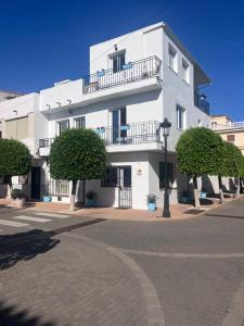 a white building with a balcony on a street at Beachfront Studio in Castillo de la Duquesa in Castillo de Sabinillas