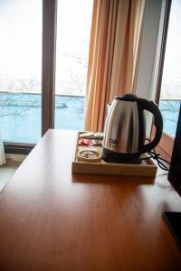 a tea kettle sitting on a wooden table next to a window at Dolphins Otel in Akçakoca