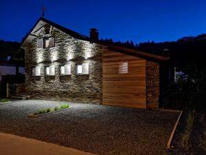 a stone house with a wooden garage at night at La Semois Et Moi in Rochehaut