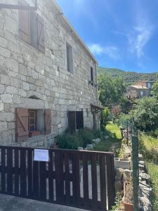 a stone house with a fence in front of it at Studio refait à neuf Chez Linda in Zicavo