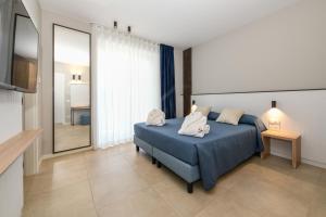 a bedroom with a blue bed and a television at Petit Hotel in Caorle +87 photos