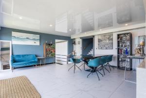 a living room with a table and blue chairs at Flamenco@Colwyn in Sheffield Beach