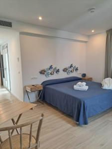 a bedroom with a blue bed and a wooden table at Aparthotel ALMARIS in Es Pujols