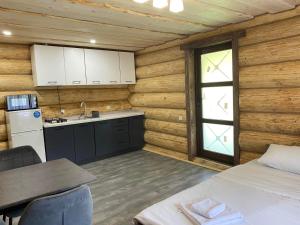 a kitchen in a wooden cabin with a table and a sink at Шепіт річки in Synevyr