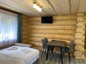 a room with a bed and a table and a tv at Шепіт річки in Synevyr