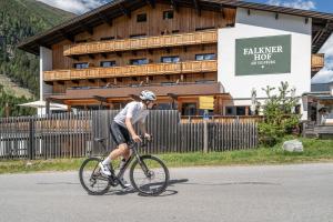 a man riding a bike in front of a building at Naturhotel Falknerhof in Niederthai