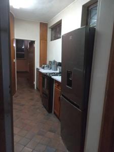 a kitchen with a black refrigerator and wooden cabinets at Sunrise and sunsets lodge previously known as leopard lodge in Kariba