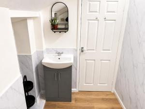 a bathroom with a sink and a white door at Cartref in Caerphilly
