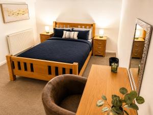 a bedroom with a bed and a chair and a table at Cartref in Caerphilly