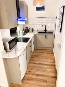 a small kitchen with white cabinets and a sink at Cartref in Caerphilly +9 photos