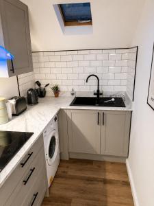a kitchen with a sink and a washing machine at Cartref in Caerphilly