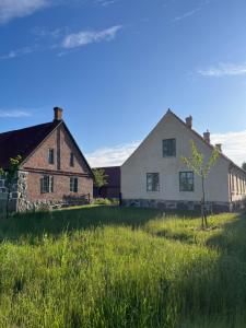 a large white house with a tree in a field at Modern seaside barn in Borrby