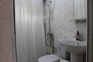 a white bathroom with a toilet and a sink at Sarytam in Bosteri +30 photos
