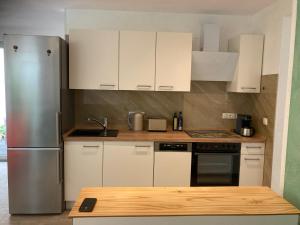 a kitchen with white cabinets and a stainless steel refrigerator at Ferienhaus Riemanns Refugium in Eutin