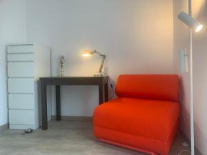 an orange chair sitting next to a desk with a lamp at Ferienhaus Riemanns Refugium in Eutin +6 photos