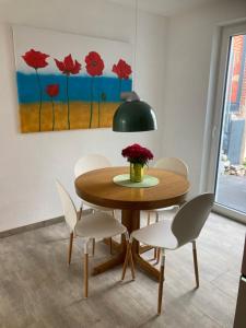 a dining room table with white chairs and a vase of flowers at Ferienhaus Riemanns Refugium in Eutin