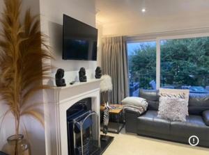 a living room with a couch and a fireplace at 27 Cae Du in Abersoch