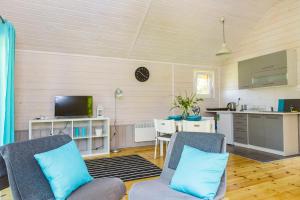 a living room with two chairs and a kitchen at Surf Domki Habenda z sauną ogrodową in Sarbsk