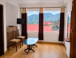 a room with a table and chairs and a large window at Hotel Bharmour View in Brāhmaur