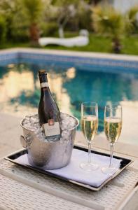 a bottle of wine in a bucket next to two glasses at Villa Verde w Warm Pool, BBQ, Concierge in Baku