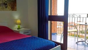 a bedroom with a bed and a view of a balcony at Hotel Bellavista S'Archittu in S'archittu Cuglieri