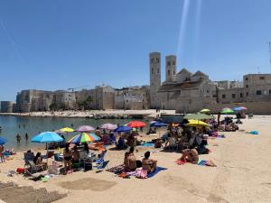 a group of people sitting on a beach with umbrellas at Marisol al puerto in Molfetta